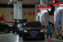 A gas station employee pumps fuel as other motorists wait in Beijing, Sunday, March 22, 2026. (AP Photo/Andy Wong)