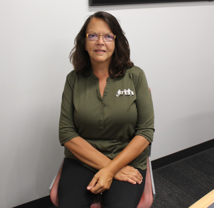 A woman in a green Life CIL shirt sits in the WGLT studio