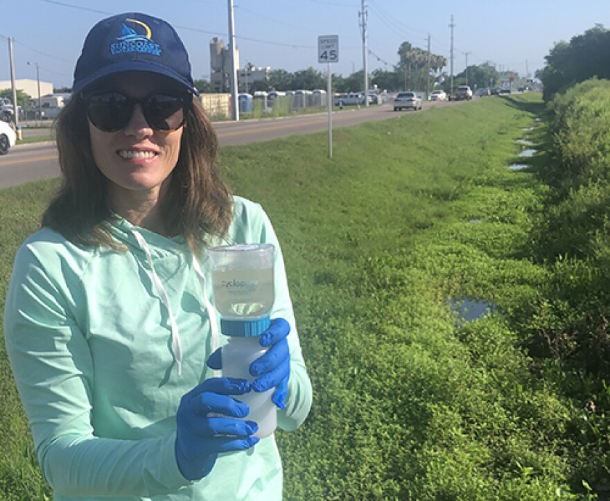 Woman outside by road wearing hat and sunglasses