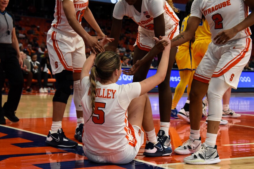 Georgia Woolley is helped up by her teammates. 