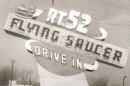 A black and white photograph of a roadside sign reading Rt. 52 Flying Saucer Drive In.