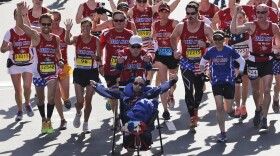 Dick and Rick Hoyt cross the finish line surrounded by supporters in the 118th Boston Marathon in Boston. (Charles Krupa/AP)