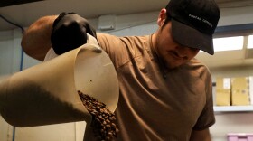 Tommy Danzi, a member of Sweetwater’s production team, pours coffee beans into a container to create a blend at their roastery on South Main Street on Monday, March 3, 2025. (Sydney Johnson/ WUFT News)