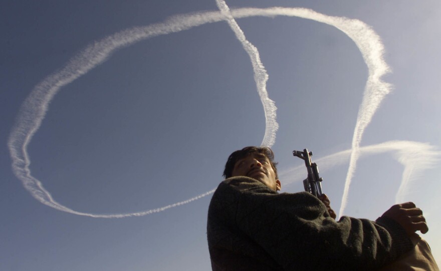 An Afghan fighter allied with the U.S. looks up at an American B-52 vapor trail during an airstrike on al-Qaida positions in eastern Afghanistan in Dec. 2001. Al-Qaida leader Osama bin Laden was in the area, but managed to escape and survive for another 10 years.