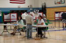 Voter check-in tables and voting booths inside a school gymnasium