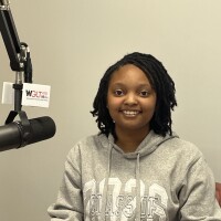 A head and shoulders image of high school student Shaylah Prince sitting at a WGLT microphone. She wears a hoodie.