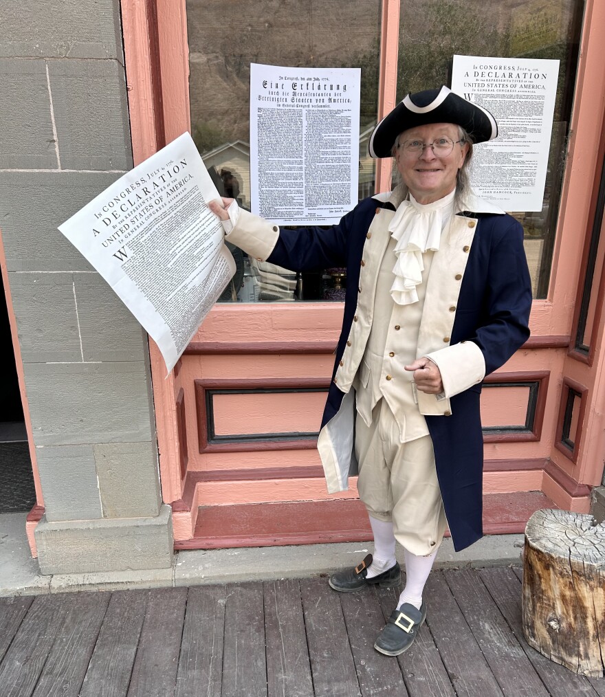 Lake City resident Schuyler Denham, dressed in colonial attire, holds a copy of the the Declaration of Independence in front of the Hinsdale County Museum.