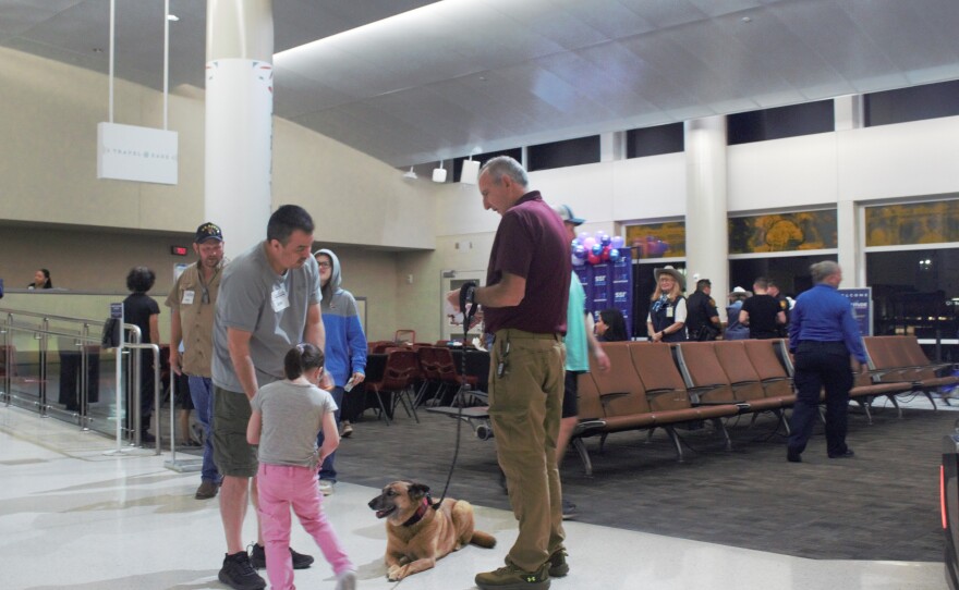 Families greet Cricket the therapy dog, who is part of Pups & Planes. Cricket was in attendance at Altitude Inclusion. Cricket helps passengers feel at ease when boarding a plane.