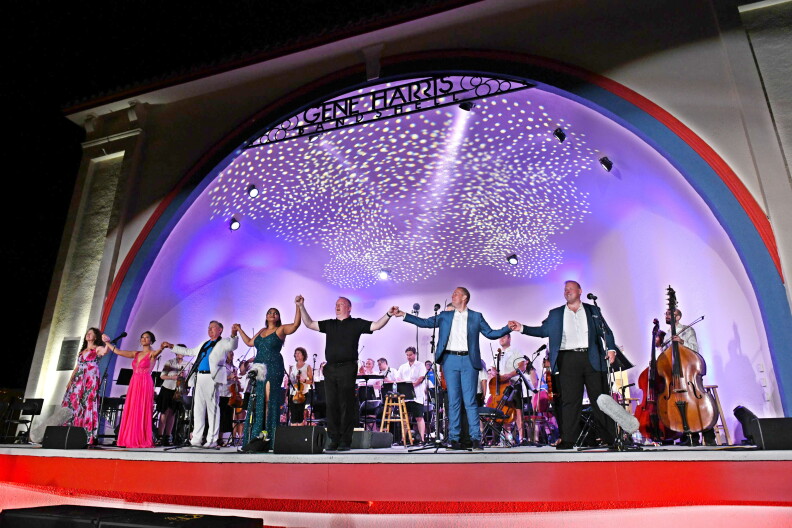 People hold hands on a stage at a previous Opera in the Park. 