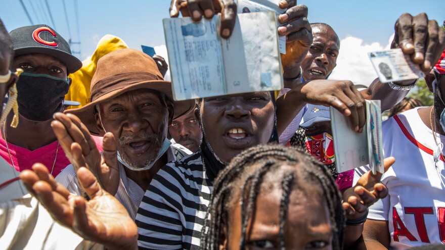 Haitian citizens hold up their passports as they gather in front of the U.S. embassy in Haiti on July 10, 2021, asking for asylum after the assassination of President Jovenel Moïse.