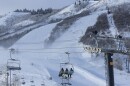 A chair lift on a mountain carries skiers up a massive hill covered in snow.