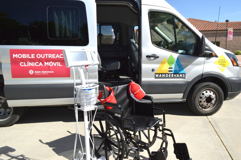 A wheelchair and blood pressure cuff are in the foreground. A van with an open side door are in the background.