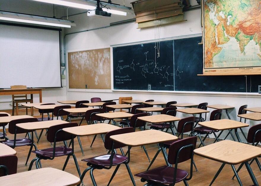 A row of desks sit in a classroom.