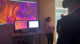 A person at the UT Dallas Center for BrainHealth explores the inside of a brain scan through VR technology, with a colorful computer screen with a brain model.