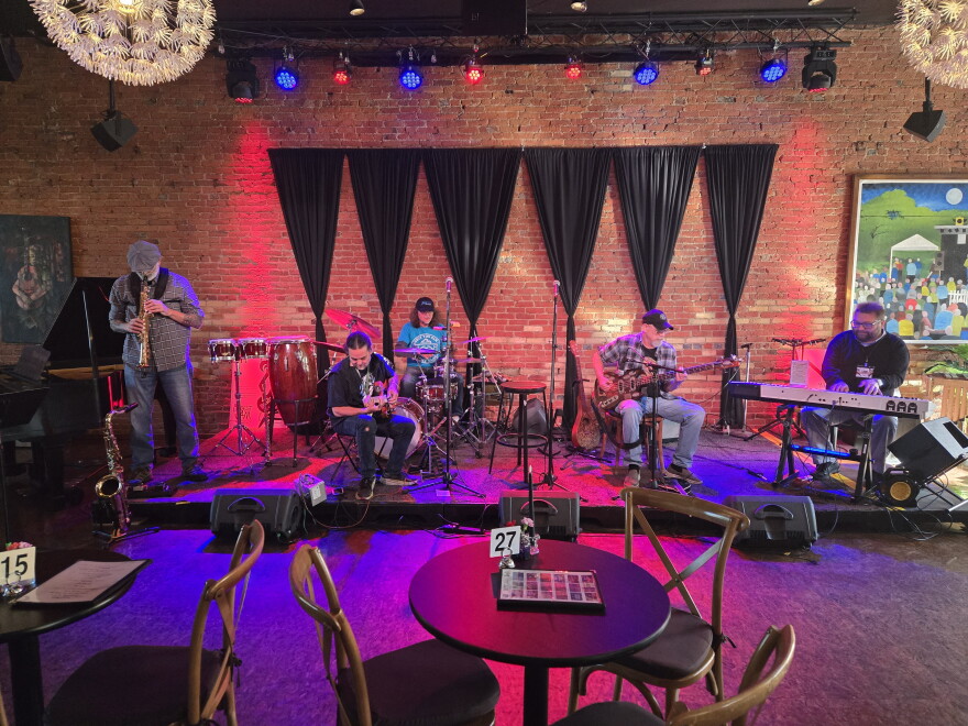 musicians on stage at UrbanBeat including a guitar player, a bass player, a piano player, a soporano saxophone player and a drummer.