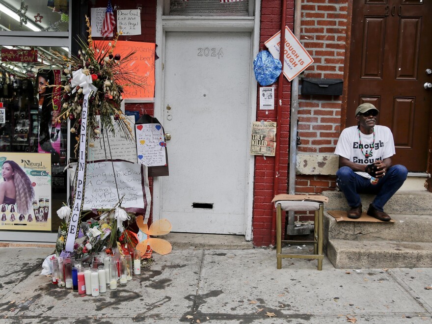 Doug Brinson sits on a stoop next to a makeshift memorial for Eric Garner in Staten Island, N.Y. Garner died after he was put in a chokehold by police officers while being arrested at the site last month for selling untaxed loose cigarettes. His death has been ruled a homicide.