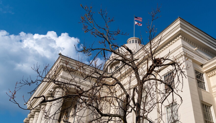 Tree branches are seen in the foreground with the Alabama Capitol building behind.