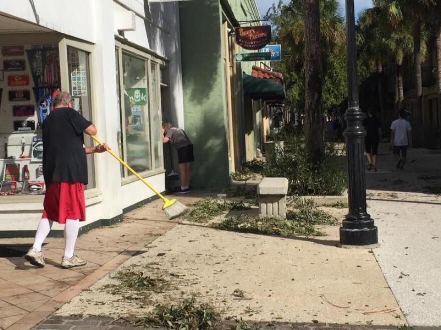 A man sweeps outside of his buisness after Hurricane Mathew passed.