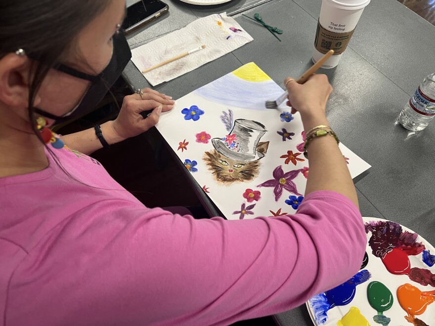 A participant in the Co-Creation project paints as classical music plays in the background