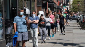 People stand in line to enter a grocery store in Washington, DC.