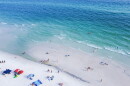 aerial shot of beach chairs, umbrellas and people swimming along white sandy beaches and turquoise water at a Santa Rosa, Florida beach