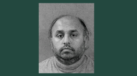 A black-and-white mugshot on a dark green background
