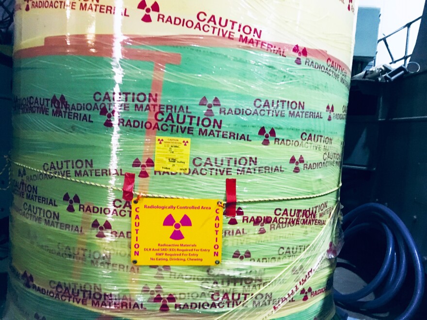 A wrapped cylinder with a nuclear waste warning sticker on it.