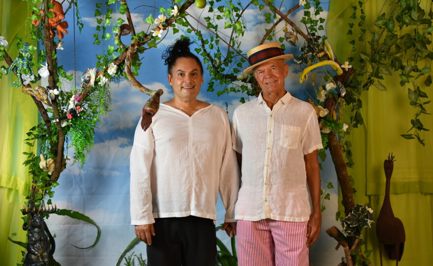 Mike and husband Jose, standing in front of art created by the late Katie Pell