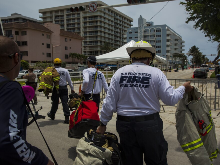 Firefighters head toward the site of the collapsed Champlain Towers South condo on July 5, 2021 in Surfside, Fla.