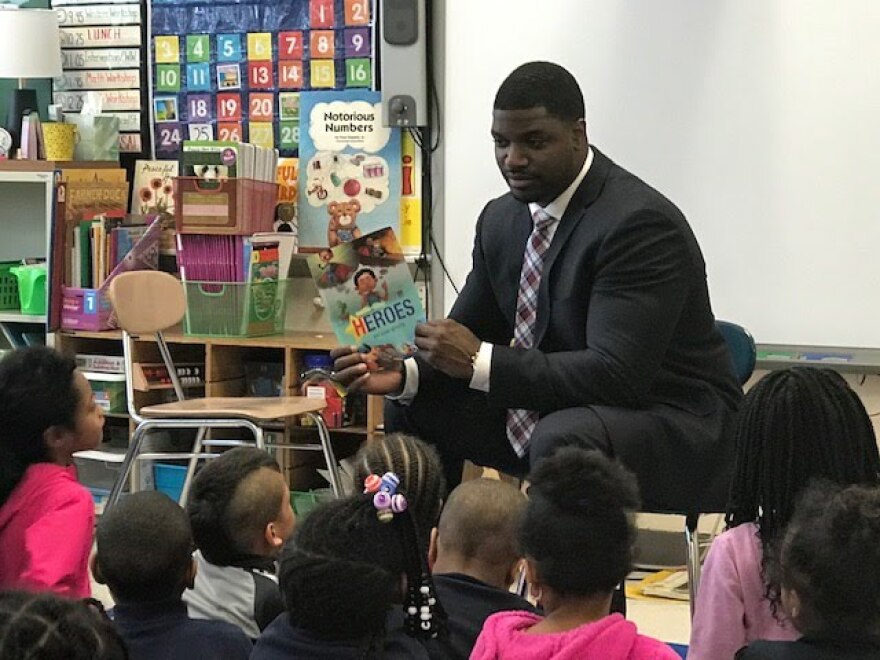 Adrian Hale reads a children's book to a classroom.