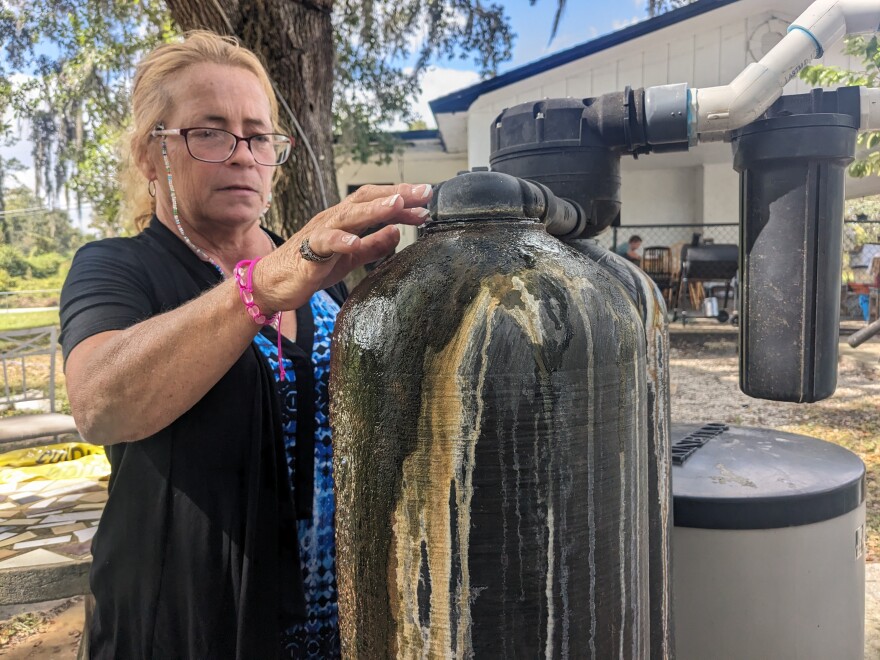 Image of a woman looking at her water softener system, which helps treat the water she gets from her private well. 