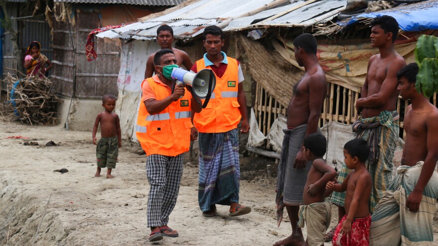 A volunteer clad in a mask urges residents to evacuate their homes Tuesday in Khulna, Bangladesh, ahead of Cyclone Amphan's anticipated landfall on Wednesday.