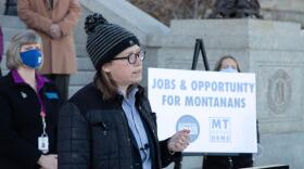 Kim Abbott stands outside the Montana Capitol at a portable lectern.