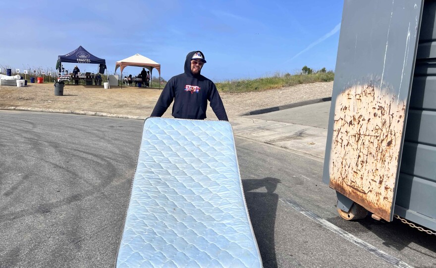 Juan Serrano, a member of Coastal Keepers, tossing a mattress into a garbage container during a clean up event at Ormond Beach in Oxnard in April. Since 2020, Coastal Keepers and other local groups have helped pick up more than 85,000 pounds of trash.