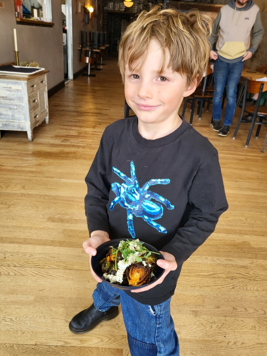 Saxon Lockhart holds a bowl of Buffalo Brussels Sprouts his father, Chef Chris Lockhart just finished making.