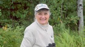 Woman holding binoculars in a green, natural area