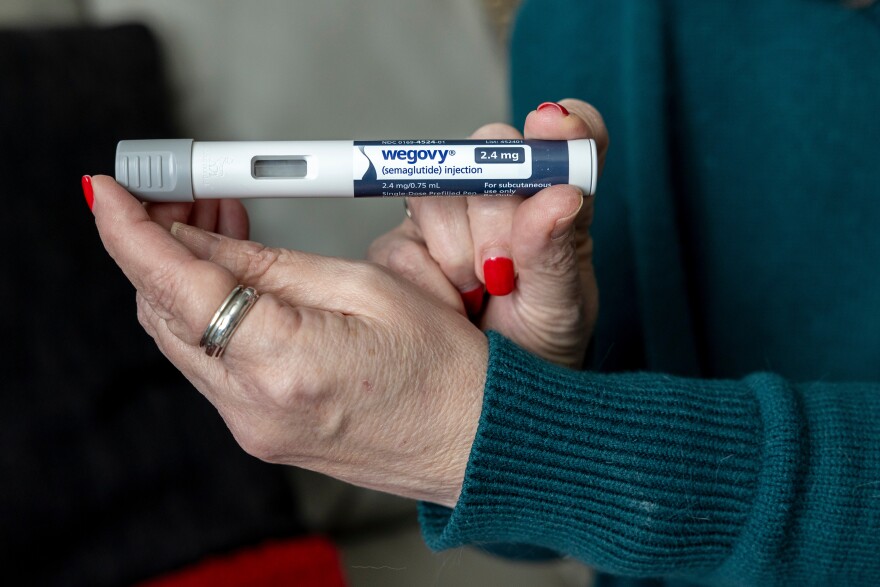 A close up of a woman's hands holding a small tube of Wegovy, an injectable weight loss medication.