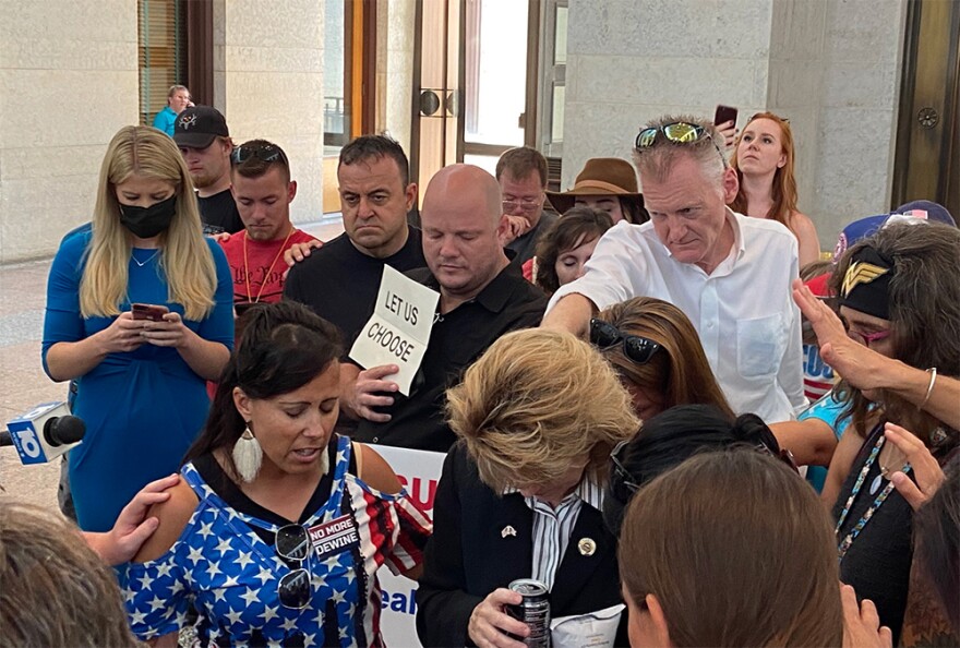 Supporters of the bill banning vaccine mandates pray and lay hands on State Rep. Jennifer Gross (bottom center) at the Ohio Statehouse on Tuesday, Aug. 23, 2021.