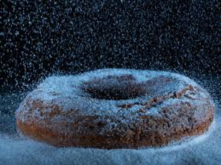 A doughnut with sugar falling on it