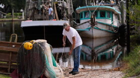 Boat owner Tony Rice, foreground, and his friend Lance Connor haul doors onto his boat to secure it as Hurricane Isaias approaches Bayou La Batre, Ala., Thursday, Oct. 8, 2026. (AP Photo/Gerald Herbert)