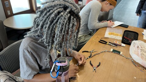 Naomi Restituyo, a RPI freshman, helps fix a necklace for an attendee at the RPI Repair Cafe.