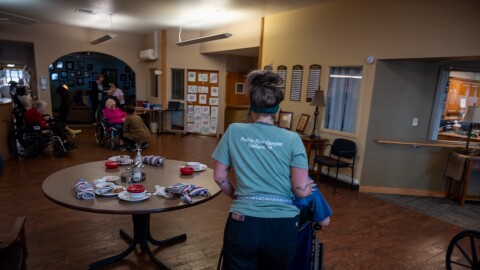 A worker at the Prairie View Nursing Home in Sanborn, Iowa, wheels a resident after lunch. The nursing home has faced chronic staffing shortages that were made worse by the COVID-19 pandemic.