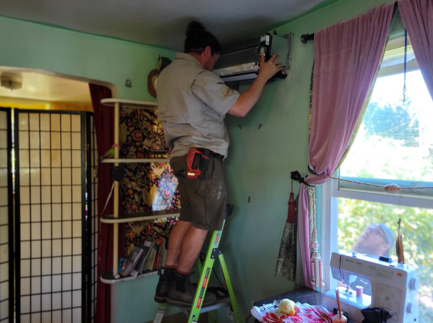 Technicians for local company Climatize, Ethan Rudawsky, left and Ryan Ward, right, work together to install a heat pump in the East Blair Housing Co-Op.