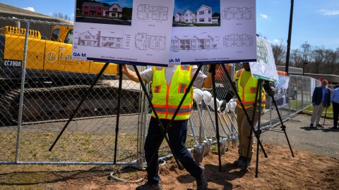 (L-R) Matt Barone and Alexander Bryden of transport architectural renderings of homes to be built where two office buildings now stand in Glastonbury at 55 Nye Road on April 14, 2026. The site will hold 64 new housing units, including 13 supportive units, to be known as Hillside Village. (Mark Mirko/Connecticut Public)