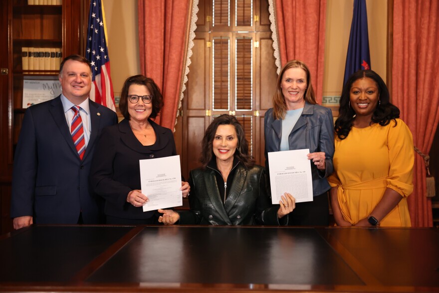 Governor Gretchen Whitmer, flanked by House and Senate leaders, presents the signed fiscal year budget.