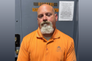 The mugshot of Officer Thomas Burkhardt in an orange collared shirt. 