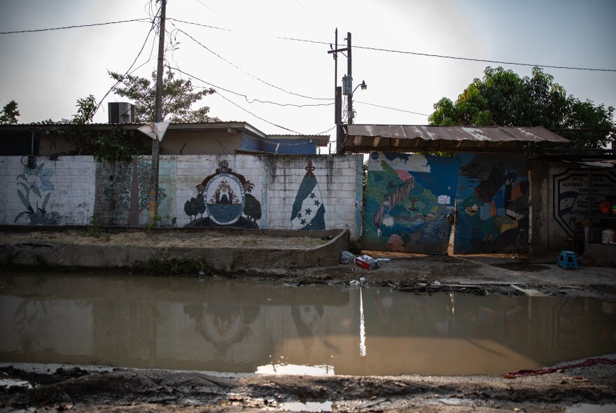 Still water pools outside a public school in the Planeta neighborhood of San Pedro Sula where the remains of the 2020 flood have yet to be cleared.