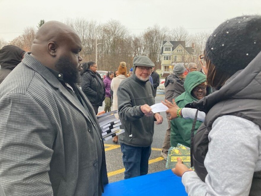 A man in a hat hands a card to a woman as others look on.