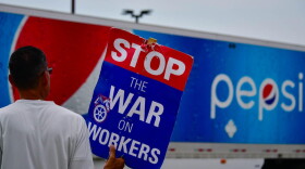A union worker pickets outside a Pepsi bottling facility in Munster as a truck leaves the driveway.
