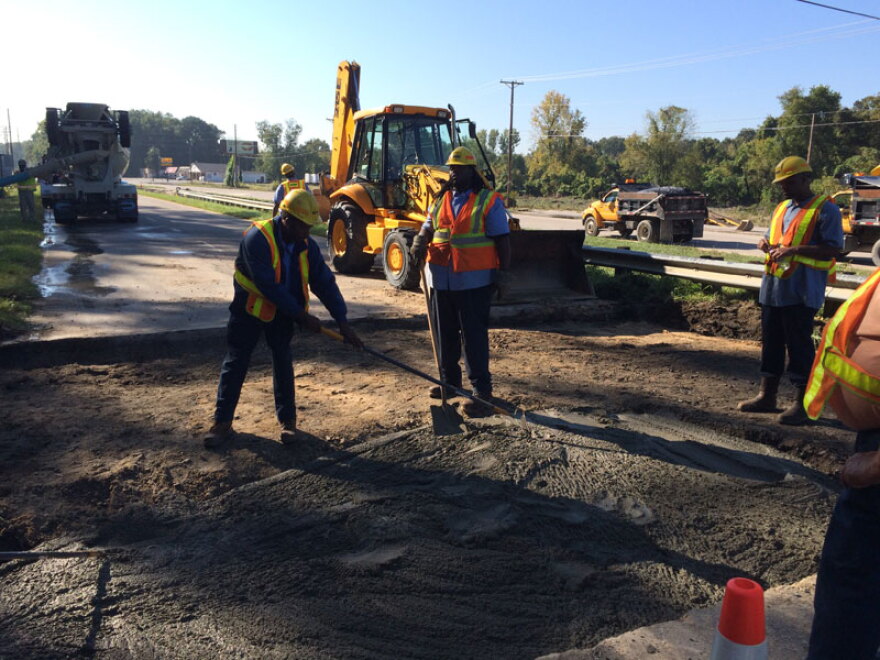 DOT workers fill the washed out bridge approach on Bluff Road at I-77.